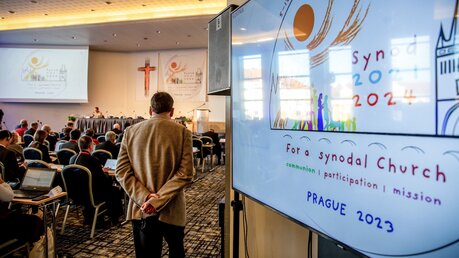 Teilnehmer während einer Working Session der Europa-Etappe der Weltsynode am 7. Februar 2023 in Prag. Vorne rechts das Logo der Weltsynode auf einem Display. / © Björn Steinz (KNA)