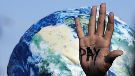  Auf einer Hand ist "Pay" zu lesen, die auf dem UN-Klimagipfel COP27 bei einem Protest der Entschädigungen für Verluste und Schäden fordert / © Peter Dejong (dpa)