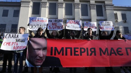 Demonstranten in Kiew halten vor der russischen Botschaft Plakate mit der Aufschrift «Wir werden niemals kapitulieren, Donbass ist die Ukraine, das Imperium muss sterben» und «Das Imperium muss sterben». / © Efrem Lukatsky/AP (dpa)