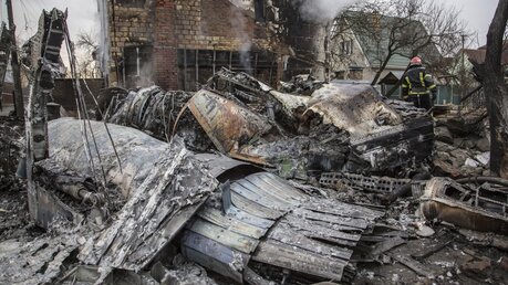 Ein Feuerwehrmann geht in Kiew zwischen den Trümmer eines Flugzeugs, das zwischen Häusern abgestürzt ist, entlang / © Oleksandr Ratushniak (dpa)