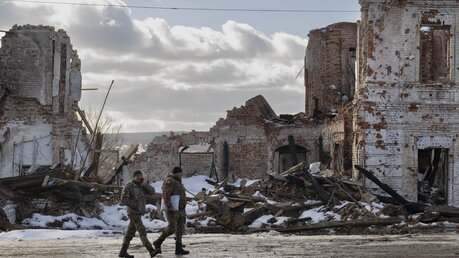 Ukrainische Soldaten gehen an einem Gebäude in Kupiansk vorbei, das durch einen Angriff zerstört wurde. / © Vadim Ghirda/AP (dpa)