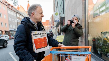 Jesuitenpater Jörg Alt verteilt vor einem Supermarkt Lebensmittel, die er zuvor bei einer Lebensmittel-Rettungsaktion aus Abfall-Containern von Supermärkten entwendet hatte / © Valeska Rehm (epd)