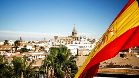 Blick auf die Kathedrale von Sevilla mit spanischer Flagge im Vordergrund / © Farbregas Hareluya (shutterstock)