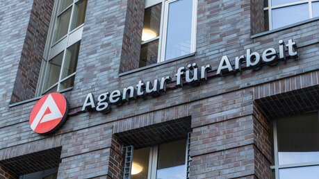 Logo und Schrift der Agentur für Arbeit auf der Fassade eines Gebäudes / © Mo Photography Berlin (shutterstock)