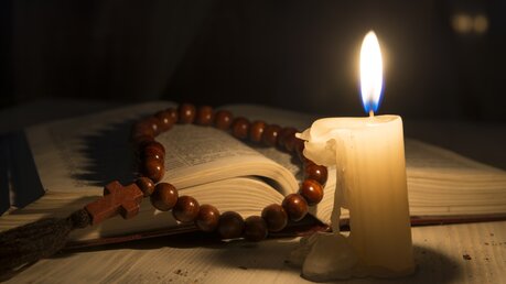 Symbolbild Gebet: Kerze, Buch und Rosenkranz / © Vladimir Kovalchuk (shutterstock)