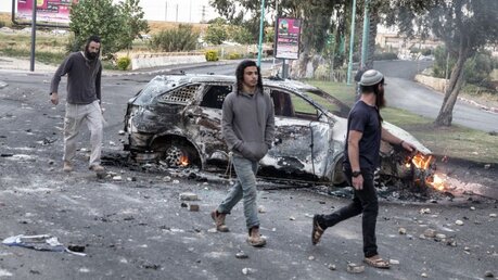 Israel, Lod: Israelis gehen an einem abgefackelten Auto vorbei / © Heidi Levine (dpa)