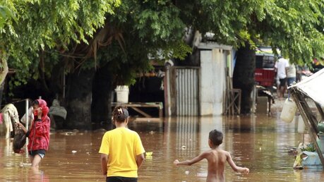 Menschen waten durch das Hochwasser nach starken Regenfällen in Dili, Osttimor / © Kandhi Barnez (dpa)