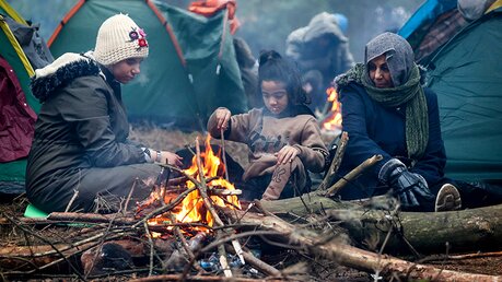 Migranten versammeln sich an der belarussisch-polnischen Grenze an einem Feuer / © Ramil Nasibulin (dpa)