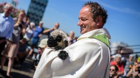 Pfarrer Rainer Maria Schießler mit einem Lamm im Arm / © Matthias Balk (dpa)