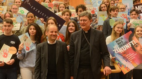 Pirmin Spiegel und Erzbischof Woelki posieren für ein gemeinsames Gruppenbild mit den Schülern im Foyer der Philharmonie. / © Tomasetti (DR)