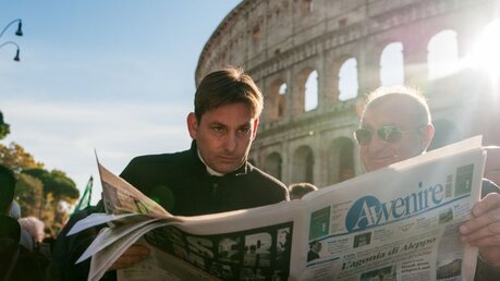Priester und Laie lesen vor dem Kolosseum in einer Zeitung / © davide bonaldo (shutterstock)