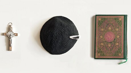 Symbolbild Weltreligionen: Kreuz, Kippa und Koran / © Jörn Neumann (epd)