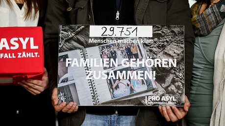 Syrerin hält ein Plakat mit der Aufschrift "Familien gehören zusammen!" / © Kay Nietfeld (dpa)