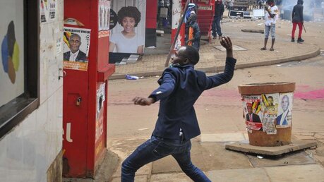 Uganda, Kampala: Ein Mann wirft bei einem Protest einen Stein (dpa)