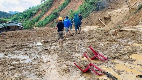 Vietnam, Quang Nam: Dorfbewohner waten durch Schlamm, nachdem ein Erdrutsch ein Dorf überschwemmt hat. / © Lai Minh Dong/VNA/AP (dpa)