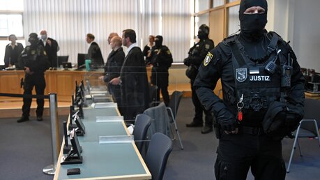 Zu Beginn des achten Prozesstages stehen Sicherheitskräfte neben den Verteidigern im Landgericht in Magdeburg / © Hendrik Schmidt (dpa)