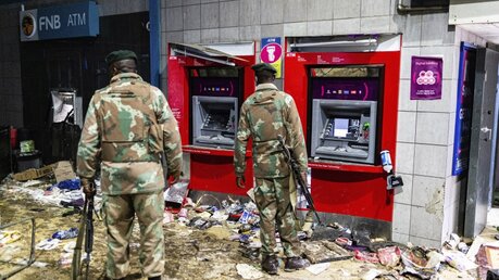 Zwei bewaffnete Soldaten stehen nach Ausschreitungen vor zwei Geldautomaten. / © Ali Greeff/AP (dpa)