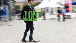 Skateboardfahrer mit einer grünen 100 in der Hand, während des 100. Deutschen Katholikentag. (KNA)