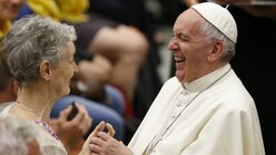Papst Franziskus lacht während er eine ältere Frau aus Lyon begrüßt, bei einer Audienz im Vatikan am 6. Juli 2016. (KNA)