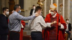 Alternativer Friedensgruß: Statt sich die Hand zu geben, berühren sich Kardinal Woelki und der Firmling an den Ellenbogen. / © Beatrice Tomasetti (DR)