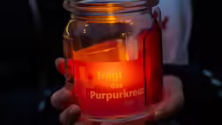 Am Rande des Synodalen Wegs: Eine Demonstrantin h&auml;lt ein Glas mit dem Aufdruck "Tragt das Purpurkreuz"  / &copy; Andreas Arnold (dpa)