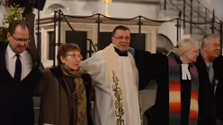 Auch Professor Schockenhoff kommt der Aufforderung, eine Friedensgeste mit dem Nachbarn auszutauschen, nach. / © Tomasetti (DR)