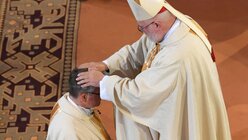 Die Handauflegung durch alle anwesenden Bischöfe gehört zum Weiheakt / © Arne Dedert (dpa)