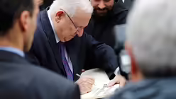 Israels Pr&auml;sident Reuven Rivlin tr&auml;gt sich in das G&auml;stebuch von Tabgha ein / &copy; Corinna Kern (dpa)