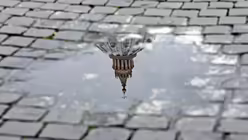  Das Kreuz auf der Kuppel des Petersdoms spiegelt sich in einer Pf&uuml;tze / &copy; Alessandro Di Meo (dpa)