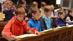 Den gr&ouml;&szlig;eren Kindern der Domsingschule erkl&auml;rt Schulseelsorger Hofer, wie eine Eucharistiefeier aufgebaut ist. / &copy; Tomasetti (DR)