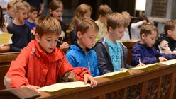 Den größeren Kindern der Domsingschule erklärt Schulseelsorger Hofer, wie eine Eucharistiefeier aufgebaut ist. / © Tomasetti (DR)