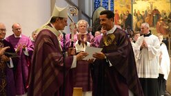 Der Erzbischof überreicht dem neuen Münsterpfarrer die Ernennungsurkunde. / © Tomasetti (DR)