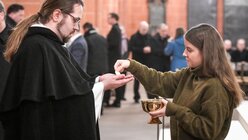 Eine junge Frau spendet die Kommunion an einen Geistlichen beim Gottesdienst während der Synodalversammlung am 31. Januar 2020 / © Harald Oppitz (KNA)