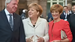 Der hessische Ministerpr&auml;sident und Bundesratspr&auml;sident Volker Bouffier begr&uuml;&szlig;t mit seiner Frau Ursula (r) am 03.10.2015 vor der Paulskirche in Frankfurt/Main Bundeskanzlerin Angela Merkel (M).  / &copy; Boris Roessler (dpa)