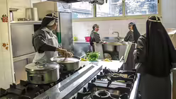 Mehrere Ordensfrauen arbeiten in der K&uuml;che, eine Ordensschwester steht am Herd an einem Topf und kocht, zwei Schwestern stehen am Sp&uuml;lbecken. (KNA)