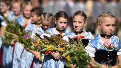 Nach der Weihe tragen die Mädchen die Kräuterbuschen zum Festplatz am See. / © Andreas Gebert (dpa)