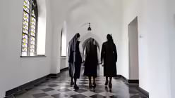 Drei Ordensfrauen der "Schwestern vom armen Kinde Jesus" laufen durch den Kreuzgang des Klosters Burtscheid am 15. August 2017 in Aachen / &copy; Cornelis Gollhardt (KNA)