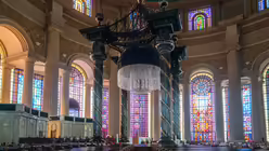 Blick über leere Kirchenbänke auf den Hauptaltar in der Basilika Notre-Dame-de-la-Paix am 24. November 2019 in Yamoussoukro, Elfenbeinküste. Die Sonne scheint durch die bunten Kirchenfenster. / © Francesco Pistilli (KNA)