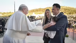Papst Franziskus begr&uuml;&szlig;t eine junge Familie mit einem kleinen M&auml;dchen am Wallfahrtsort Ta Pinu / &copy; Paul Haring (KNA)