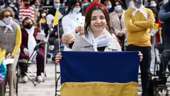 Eine junge Frau h&auml;lt eine ukrainische Nationalflagge und l&auml;chelt bei einer Messe mit Papst Franziskus in Floriana (Malta) / &copy; Paul Haring (KNA)