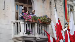 Ein Kind, eine Frau und ein Mann stehen auf einem Balkon bei einer Messe mit Papst Franziskus in Floriana (Malta) / &copy; Paul Haring (KNA)