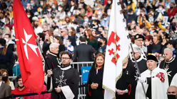 Mitglieder des Souver&auml;nen Ritter- und Hospitalordens vom Heiligen Johannes zu Jerusalem von Rhodos und von Malta (SMRO) schwenken Fahnen mit dem Malteserkreuz bei einer Messe mit Papst Franziskus / &copy; Paul Haring (KNA)