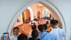 Junge Männer schauen von einer Empore auf Papst Franziskus und machen Fotos mit dem Smartphone, bei einem Treffen mit Bischöfen, Priestern, Diakonen, Ordensleuten, Seminaristen und pastoralen Mitarbeitern in der Kathedrale der Unbefleckten Empfängnis in Dili (Osttimor) / © Vatican Media/Romano Siciliani (KNA)