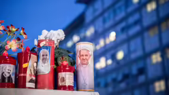 Blumen und Votivkerzen, einige mit dem Abbild von Papst Franziskus, liegen vor dem Gemelli-Krankenhaus in Rom. / © Pablo Esparza (KNA)