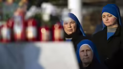 Ordensfrauen beten vor Blumen und Votivkerzen, für Papst Franziskus vor dem Gemelli-Krankenhaus in Rom. / © Alessia Giuliani (KNA)