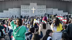 Menschen schwenken Libanesische Fahnen und warten am 2. Dezember 2025 vor einer Messe an der Beirut Waterfront in Beirut (Libanon) auf Papst Leo XIV. / © Andrea Krogmann (KNA)