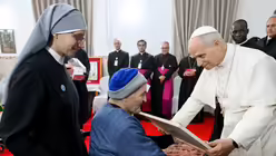 Papst Leo XIV. bekommt ein Bild &uuml;berreicht von einem Mann bei seinem Besuch im Seniorenheim der "Kleinen Schwestern der Armen", am 14. April 2026 in Annaba (Algerien) / &copy; Vatican Media/Romano Siciliani (KNA)