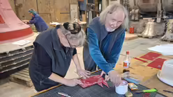 Künstler Gert Weber (r.) hilft beim Verzieren der falschen Glocke (Glockengießerei Grassmayr)
