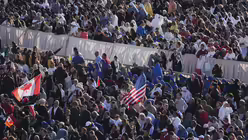 Die kanadische und die US-amerikanische Flagge werden geschwenkt, als sich die Menschen auf dem Petersplatz vor der Eröffnungsmesse des Pontifikats von Papst Leo XIV. im Vatikan versammeln / © Jacquelyn Martin/Pool AP/AP (dpa)