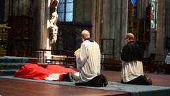 Am Karfreitag streckt sich der Kardinal zunächst auf dem Boden aus. Zu seinen Füßen Domzeremoniar Stockem. / © Beatrice Tomasetti (DR)